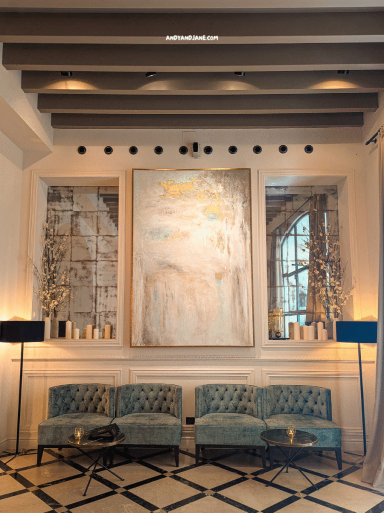 A stylish lounge area in Hotel Basilica, Palma featuring tufted teal chairs, modern art, candles, and elegant decor against a refined interior backdrop.