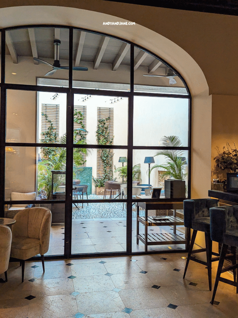 A stylish hotel interior with a view of a serene outdoor garden, featuring plush seating and modern decor.