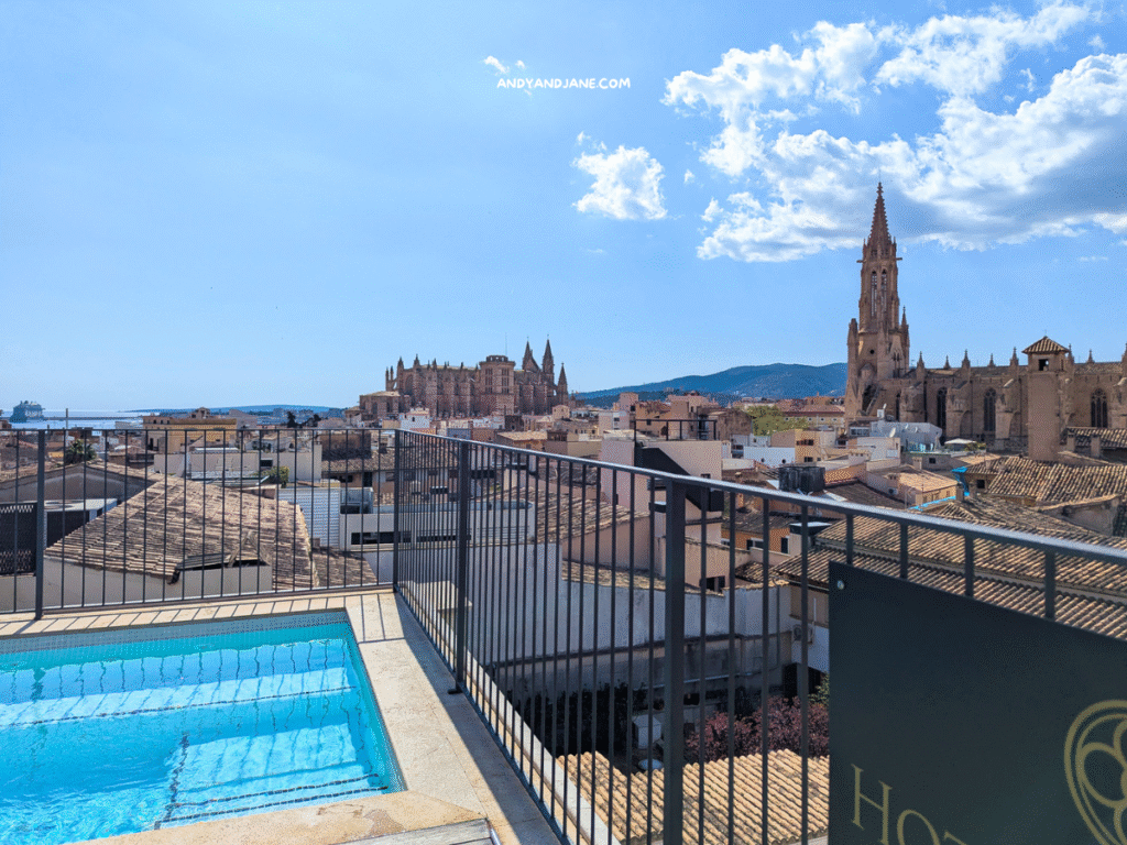 Sky view from a hotel rooftop pool overlooking Palma's historic buildings, including the impressive cathedral and coastal scenery.